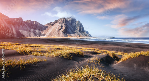 Scenic image of famous Stokksnes cape and Vestrahorn Mountain with colorful dramatic sky during sunset in Iceland. Iconic location for landscape photographers. Amazing nature scenery of World.