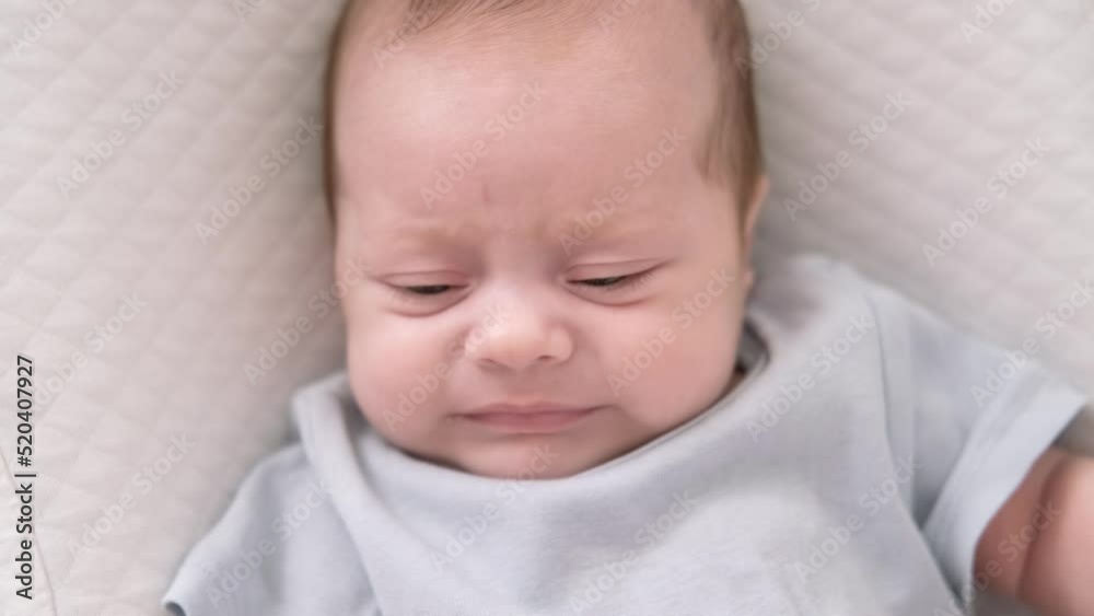 Dissatisfied, crying, upset, sad Newborn baby boy lying in nursery cocoon with blue clothes on bed in bedroom at home, baby morning Dissatisfied, crying, upset, sad Newborn baby boy lying in nursery cocoon with blue clothes on bed in bedroom at home, baby morning