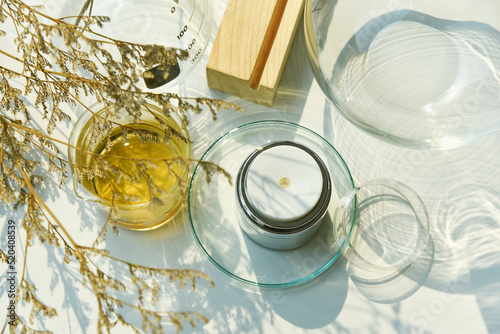 Cosmetic pump bottle container on sunlight and leaves plant shadow background, Skincare facial cream, Beauty product with warm mood and tone.