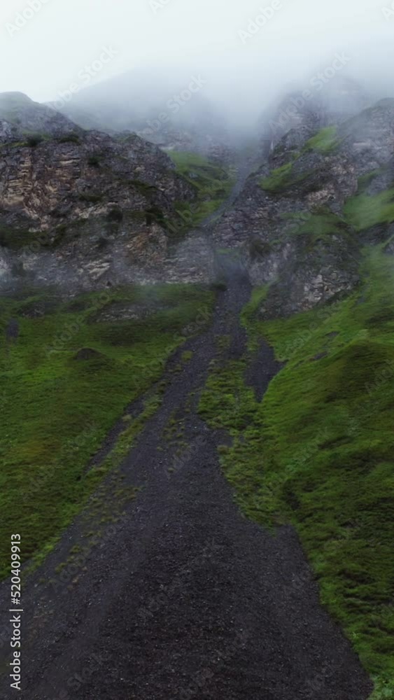 View of the steep rocky mountains through a veil of clouds from a quadcopter View of the steep rocky mountains through a veil of clouds from a quadcopter