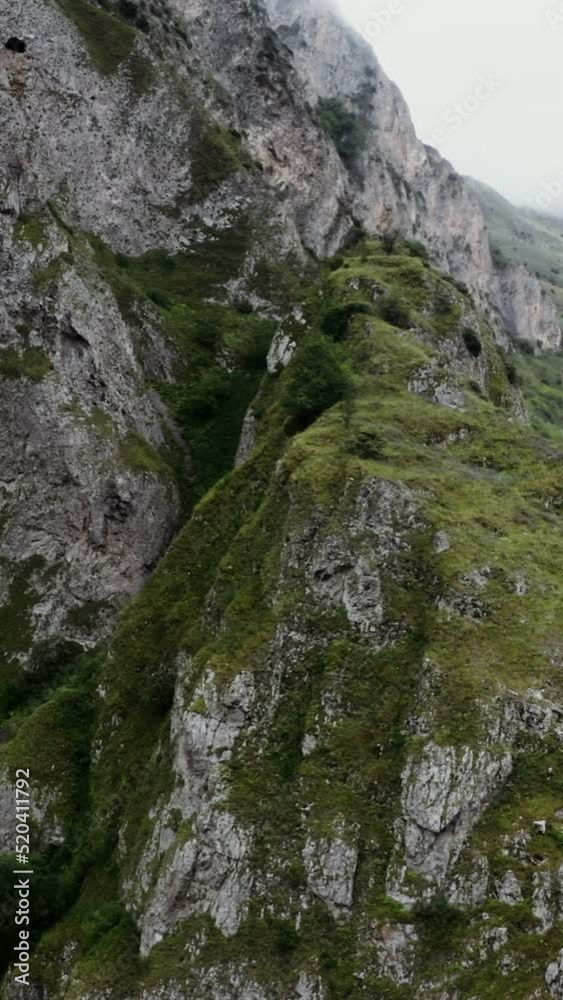 A rocky mountain slope overgrown with greenery, close-up. mountain valley with a river and fields in the lowland. A rocky mountain slope overgrown with greenery, close-up. mountain valley with a river and fields in the lowland.