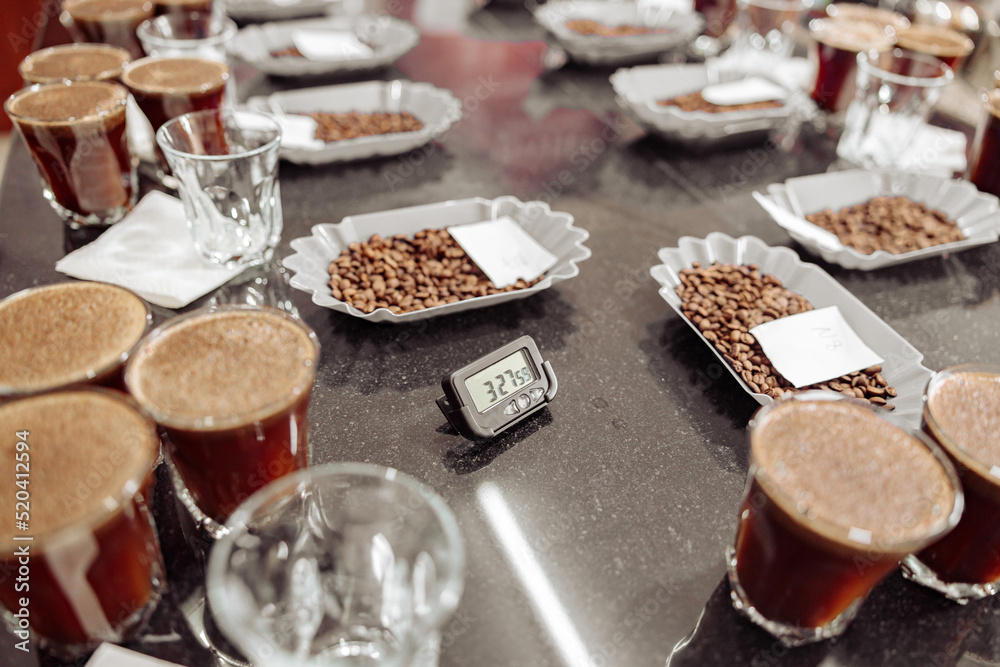 Top view of glasses of coffee and bowls with roasted coffee beans ready for a coffee tasting, timer on the table