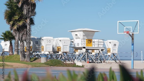 Palm trees and basketball sport field or court on beach, California coast, USA. Streetball playground on shore and lifeguard stand, tower ot station. Mission beach, San Diego. Hoop, backboard and sky.