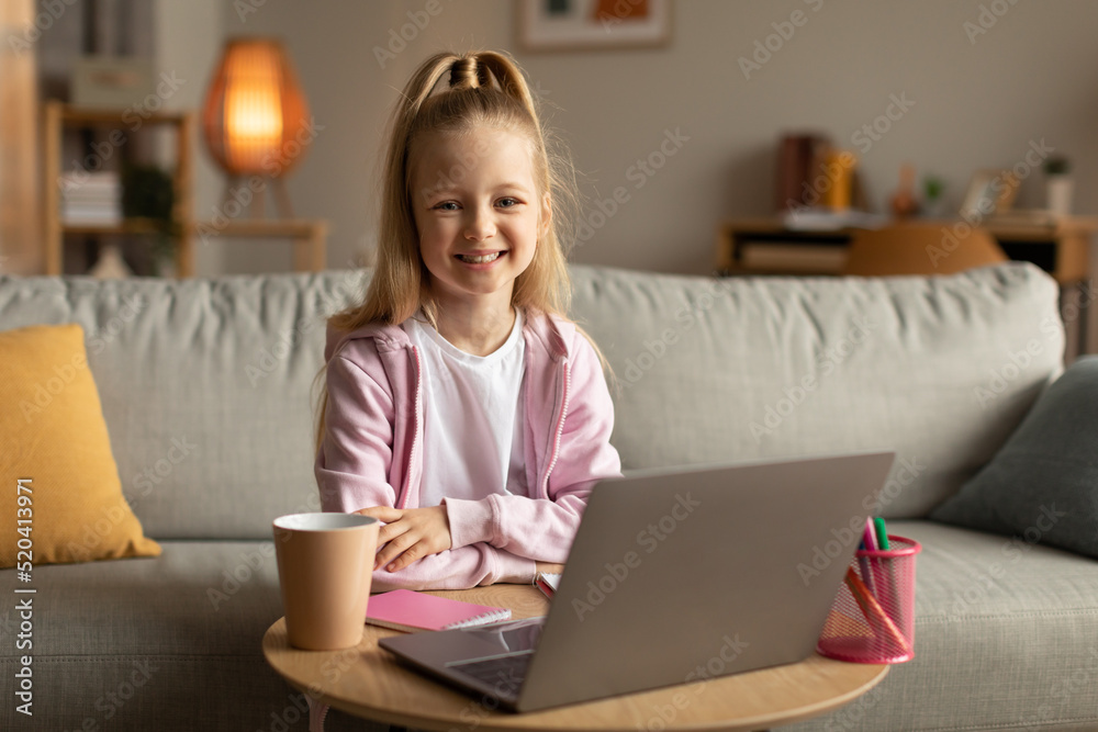 Cheerful Schoolgirl Sitting At Laptop Holding Hands On Desk Indoor Cheerful Schoolgirl Sitting At Laptop Holding Hands On Desk Indoor