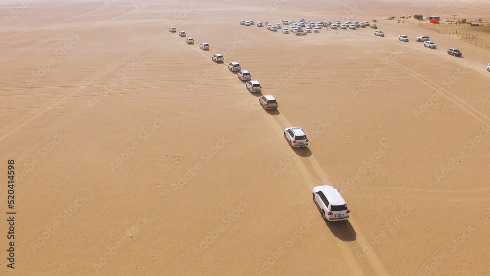 4x4 SUVs cars driving through the sand dunes in the desert of Abu Dhabi