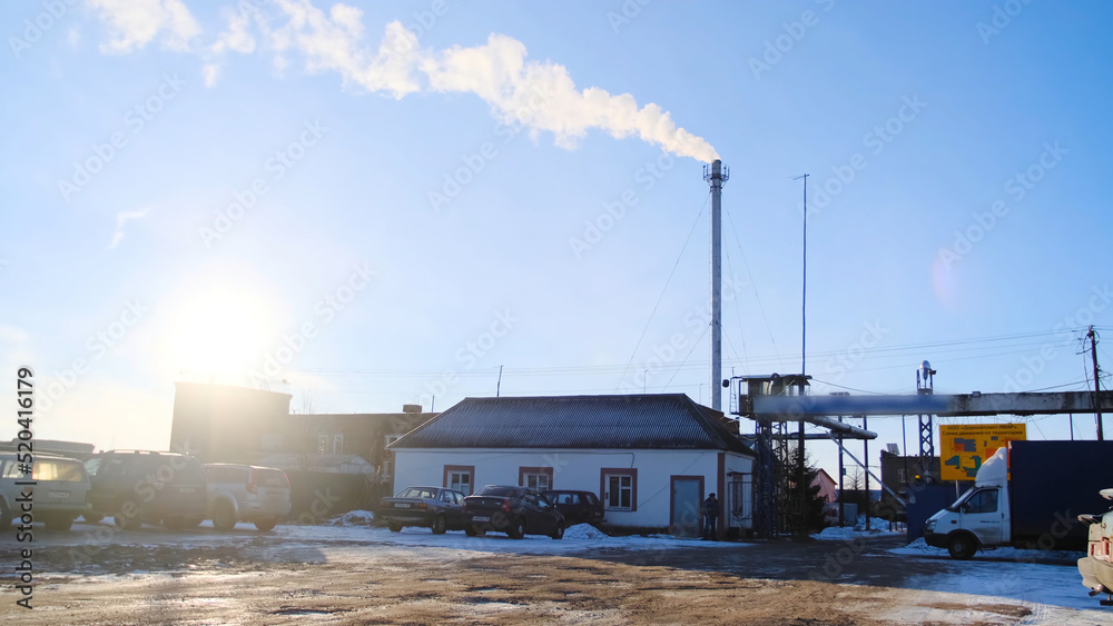 Obraz premium View of site of industrial plant on background of blue sky. Stock footage. Tractor leaves industrial protected area against blue sky with bright sun