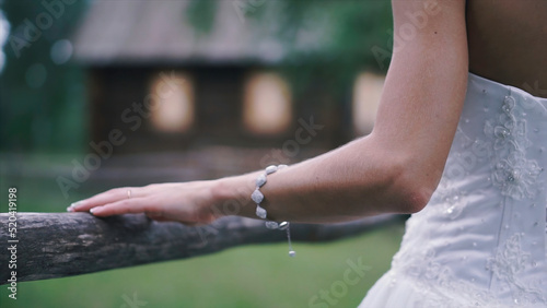 Close-up of bride's hands with on beautiful white wedding dress. Clip. Newlywed girl in outdoor near wooden fence