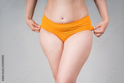 Fat woman in orange panties on a gray background, thick female thighs photo