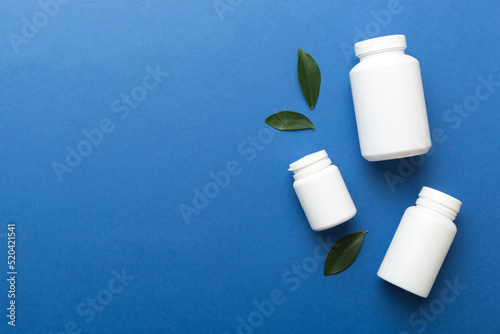 supplement pills with medicine bottle health care and medical top view. Vitamin tablets. Top view mockup bottle for pills and vitamins with green leaves, natural organic bio supplement, copy space