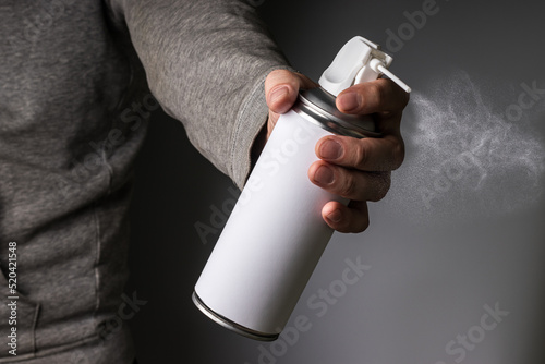 Fotografie Person hand holding and spraying a blank aluminum spray can, aerosol can and sma