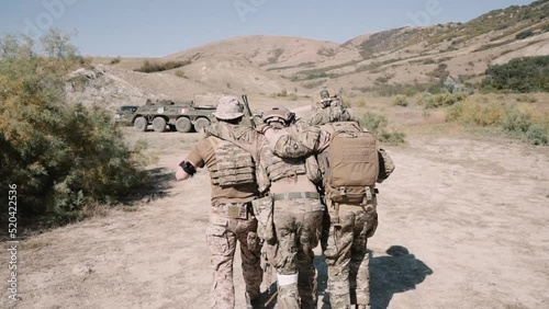 U.S. Navy SEALS carry under the arms of a wounded soldier photo