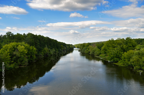 River in a forest area against a blue sky © Oleksandrum