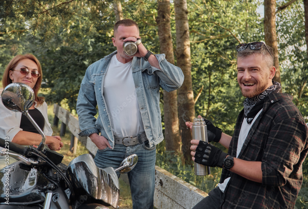 Meeting A company of friends of motorcyclists bikers on motorcycles stopped on the roadside having fun and drinking tea Meeting A company of friends of motorcyclists bikers on motorcycles stopped on the roadside having fun and drinking tea