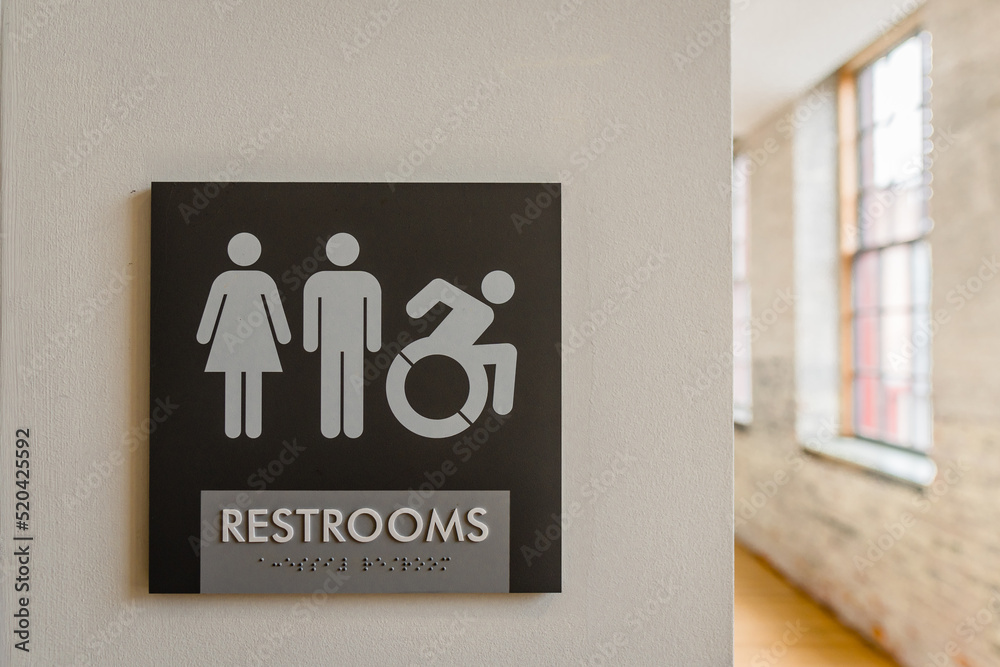 Close-up of unisex bathroom sign against neutral colored wall with ...