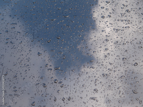 Water drops on the hood of a metallic black car and the reflection of clouds and sky after a storm photo