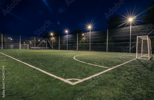 Soccer field with artificial green grass near the school. Amateur football field. Summer evening