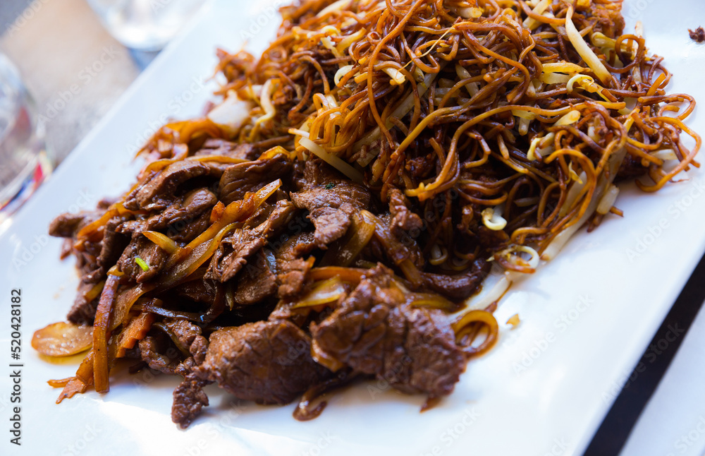 Asian cuisine. Delicious beef with onions and noodles served on white plate