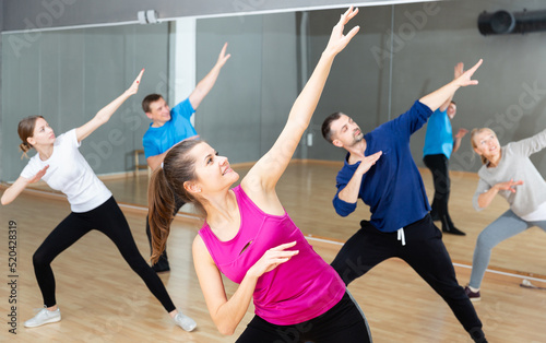 Portrait of young emotional woman doing exercises during group class in dance center