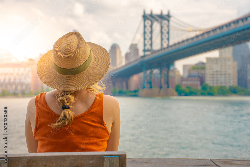 Back view of attractive young woman with hat in New York City. Travel, freedom and adventure concept.