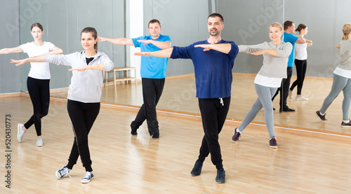 Group of different ages women and men doing stretching exercises warming up at dance class