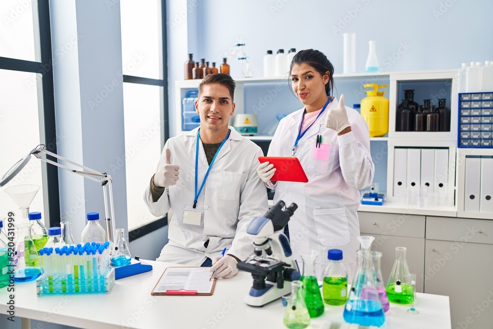 Young doctors working at scientist laboratory smiling happy and positive, thumb up doing excellent and approval sign Young doctors working at scientist laboratory smiling happy and positive, thumb up doing excellent and approval sign