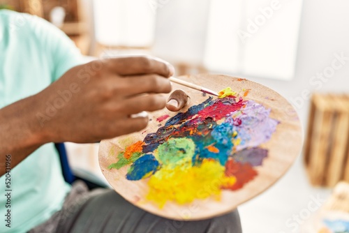 Hand of african american artist man mixing color on palette at art studio.