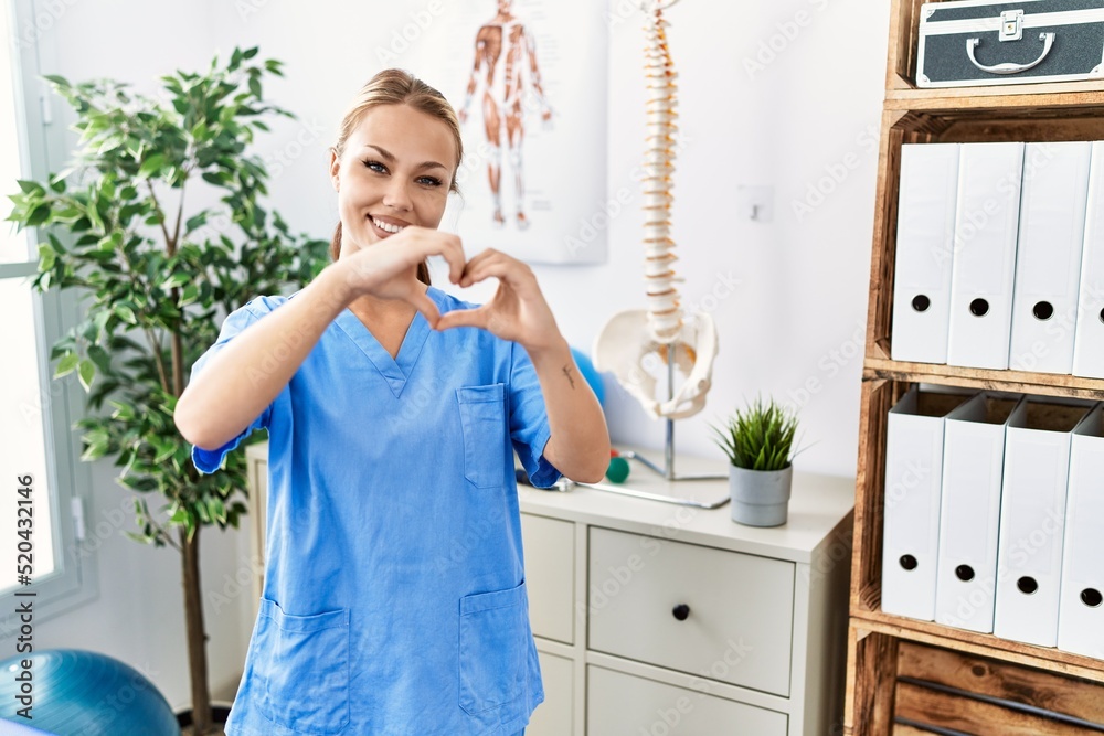 Young caucasian woman working at pain recovery clinic smiling in love doing heart symbol shape with hands. romantic concept. Young caucasian woman working at pain recovery clinic smiling in love doing heart symbol shape with hands. romantic concept.