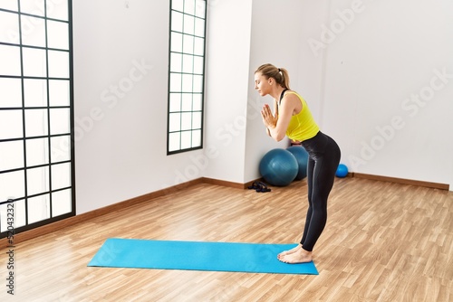 Young blonde girl training yoga at sport center.