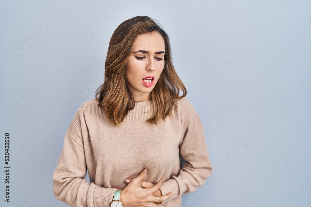 Obraz premium Young woman standing over isolated background with hand on stomach because indigestion, painful illness feeling unwell. ache concept.