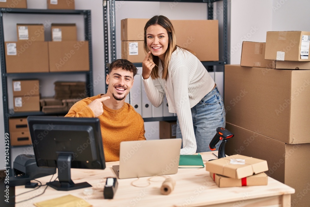 Young couple working at small business ecommerce smiling happy pointing with hand and finger Young couple working at small business ecommerce smiling happy pointing with hand and finger