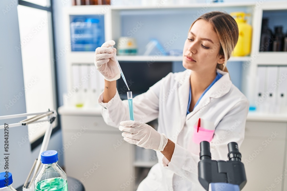 Young hispanic woman scientist pouring liquid on test tube at laboratory Young hispanic woman scientist pouring liquid on test tube at laboratory