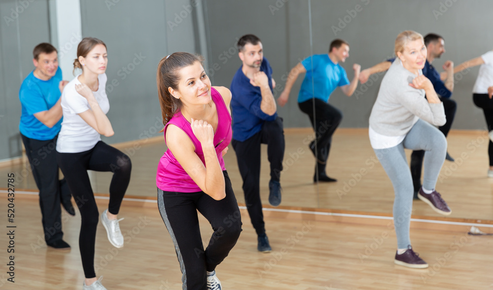 Fototapeta premium Smiling females and males doing Zumba dance workout during group classes in fitness center