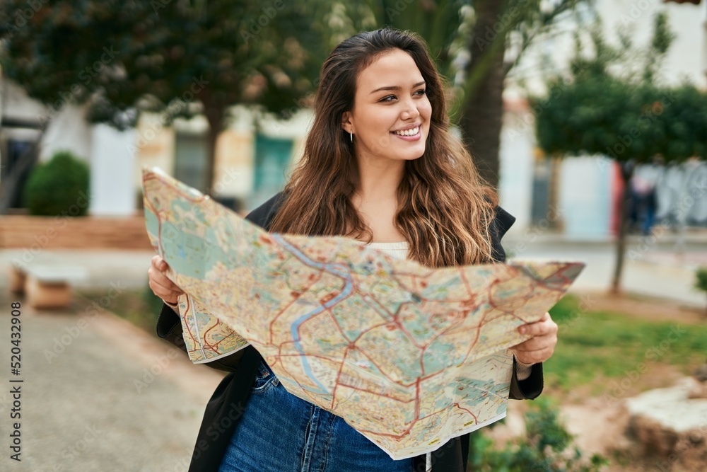 Naklejka premium Young hispanic tourist woman holding map at the city.