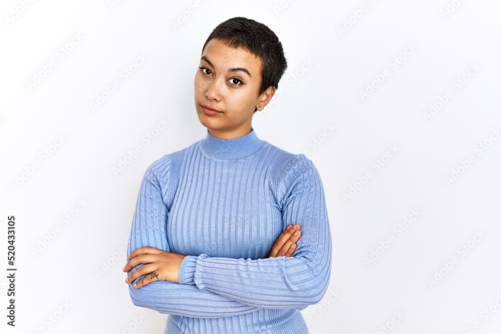 Young hispanic woman with short hair standing over isolated background skeptic and nervous, disapproving expression on face with crossed arms. negative person. Young hispanic woman with short hair standing over isolated background skeptic and nervous, disapproving expression on face with crossed arms. negative person.