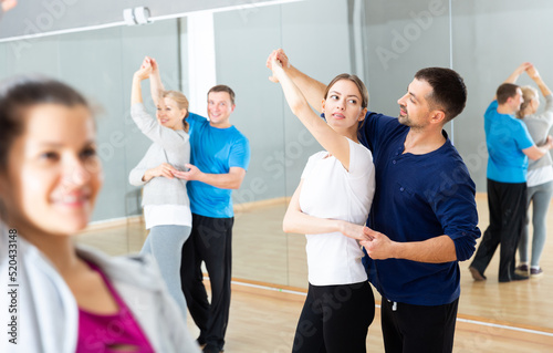 Cheerful adults learning to dance kizomba with partners in dancing group class