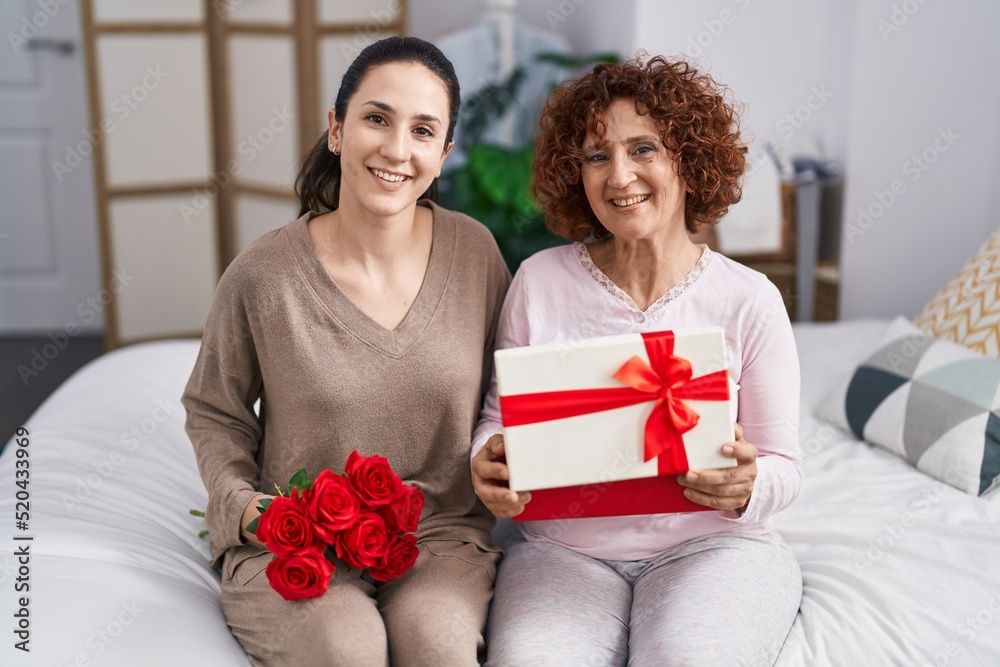Two women mother and daughter surprise with gift and flowers Two women mother and daughter surprise with gift and flowers