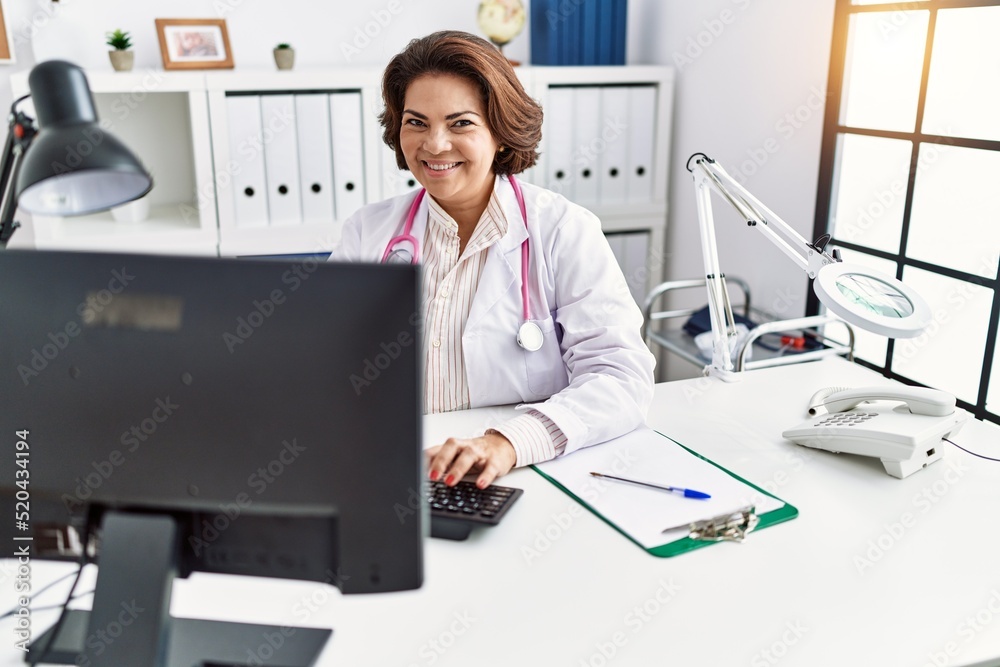 Middle age hispanic woman wearing doctor uniform working at clinic