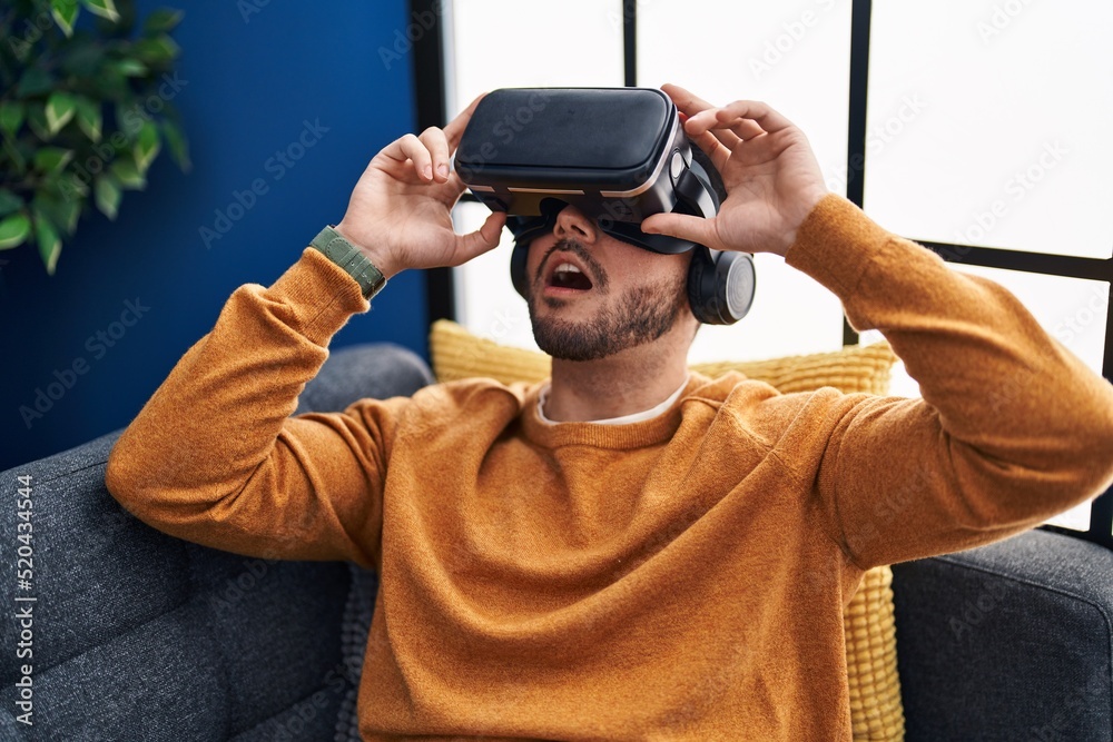 Young hispanic man playing video game using virtual reality glasses at home Young hispanic man playing video game using virtual reality glasses at home