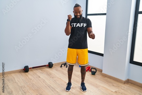 African american man working at fitness gym celebrating surprised and amazed for success with arms raised and eyes closed