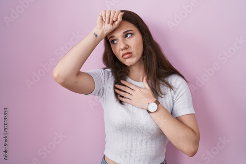Young hispanic girl standing over pink background touching forehead for illness and fever  flu and cold  virus sick