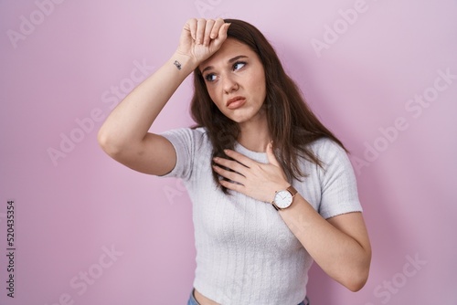 Young hispanic girl standing over pink background touching forehead for illness and fever, flu and cold, virus sick