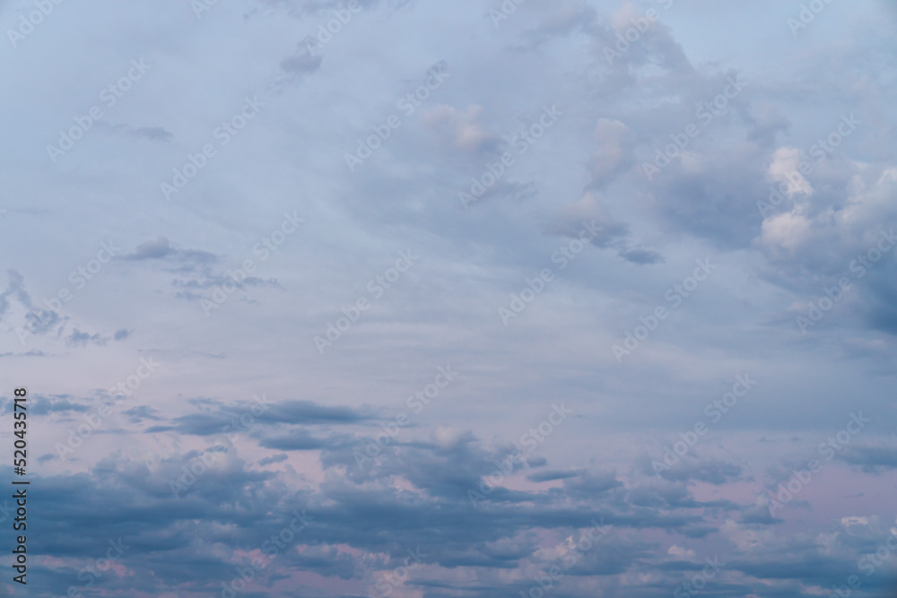 Fototapeta premium Beautiful high resolution sunset sky replacement background with a layer of low lying cumulus clouds with deep blue tones and textured upper clouds with hints of pink, and yellow hues.
