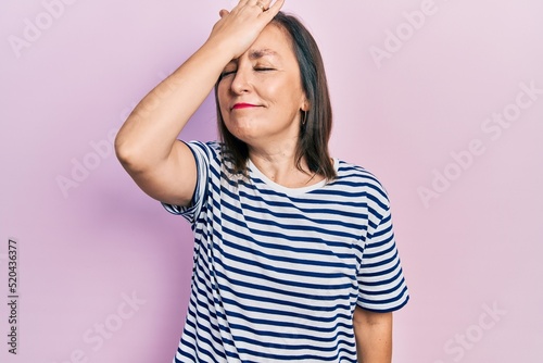 Middle age hispanic woman wearing casual clothes surprised with hand on head for mistake, remember error. forgot, bad memory concept.