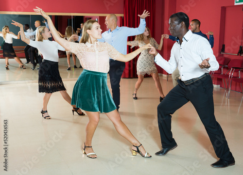 Portrait of young people dancing lindy hop in pairs in modern dance hall