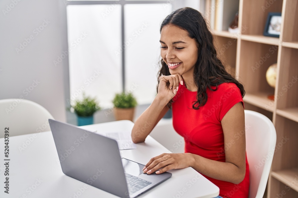 Young african american woman using laptop sitting on table at home Young african american woman using laptop sitting on table at home