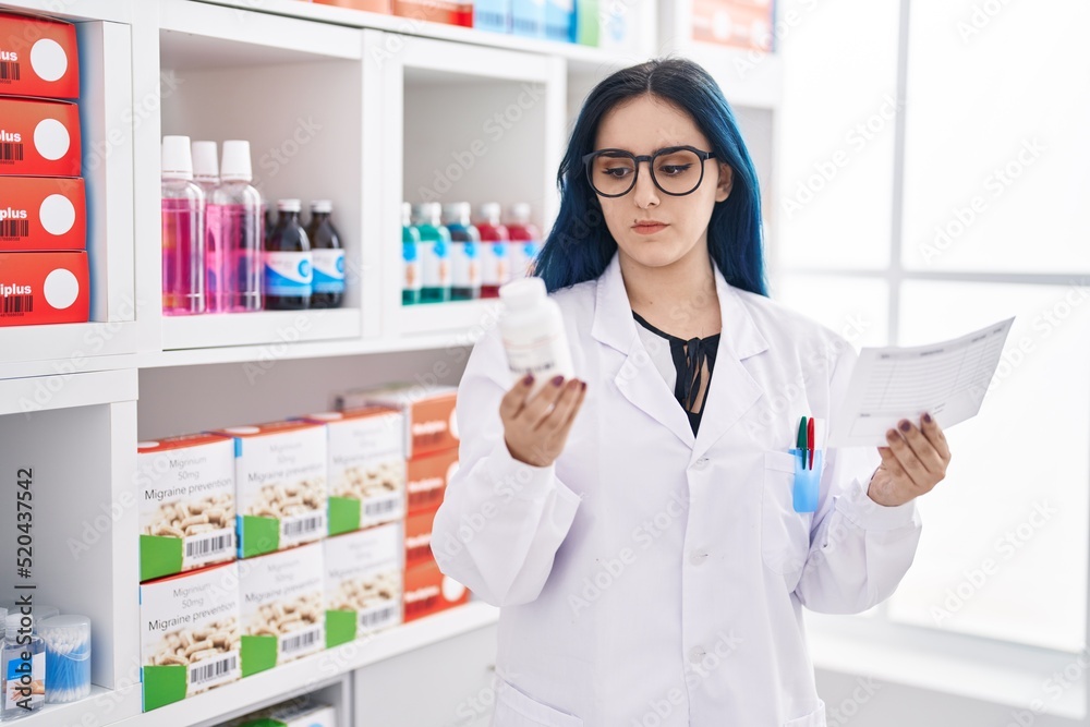 Young caucasian woman pharmacist holding pills bottle reading prescription at pharmacy