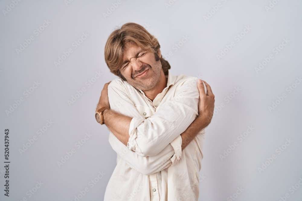 Middle age man standing over isolated background hugging oneself happy and positive, smiling confident. self love and self care Middle age man standing over isolated background hugging oneself happy and positive, smiling confident. self love and self care