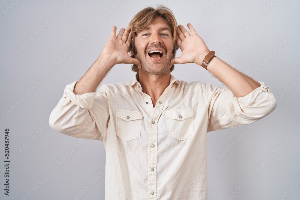 Middle age man standing over isolated background smiling cheerful playing peek a boo with hands showing face. surprised and exited Middle age man standing over isolated background smiling cheerful playing peek a boo with hands showing face. surprised and exited