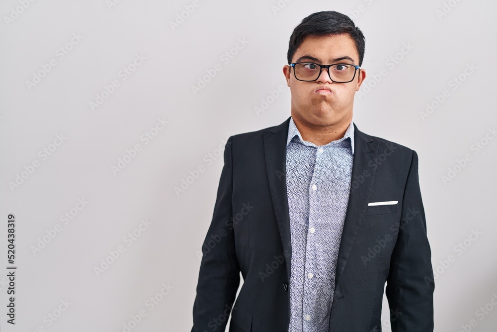 Young hispanic man with down syndrome wearing business style puffing cheeks with funny face. mouth inflated with air, crazy expression. - obrazy, fototapety, plakaty 