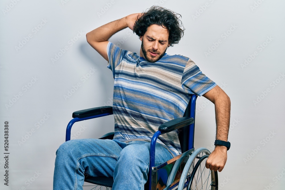Handsome hispanic man sitting on wheelchair stretching back, tired and relaxed, sleepy and yawning for early morning Handsome hispanic man sitting on wheelchair stretching back, tired and relaxed, sleepy and yawning for early morning